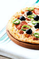 Pizza with salami, jalapeno pepper and black olives. Home made food. Concept for a tasty and hearty meal. Close up