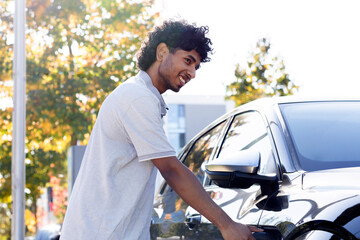 portrait of a young man with a charger by an electric car