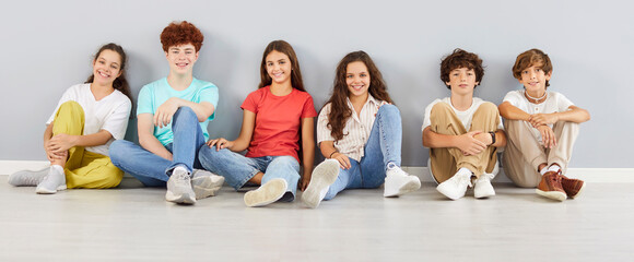 Portrait of a smiling school children looking cheerful at the camera on gray wall background....