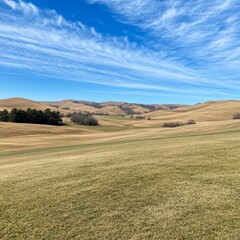 Rolling hills and blue sky with wispy clouds.