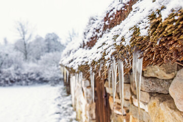 Old croft with icicles hanging from a thatched roof © Lars Johansson