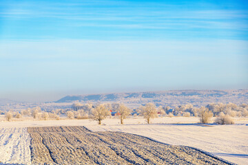 Plowed field in a wintry rural landscape with snow and frost on a cold sunny winter day