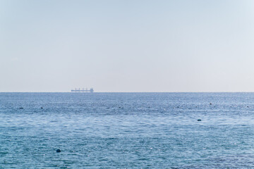 Obraz premium Calm blue sea with the silhouette of a large ship on the horizon