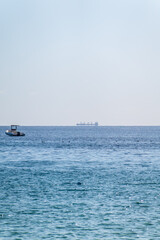 Fototapeta premium Calm blue sea with the silhouette of a large ship on the horizon