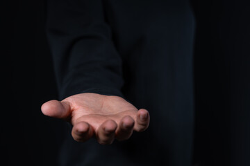 Fototapeta premium Open hand gesture against dark background, concept of giving or receiving.