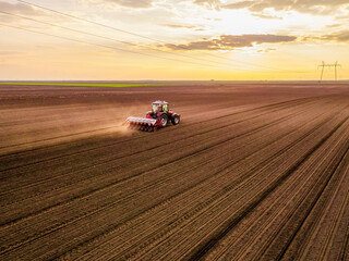 Aerial shot of a farmer seeding, sowing crops at field. Sowing is the process of planting seeds in the ground as part of the early spring time agricultural activities.