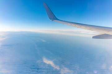 View from the airplane window at a beautiful cloudy sky and the airplane wing