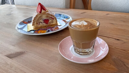 Cortado drink and Budapest dessert served on a wooden table.