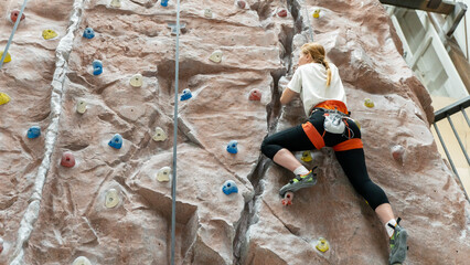 woman on a climbing wall climbs up the wall