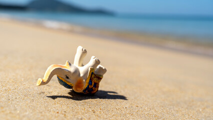 Obraz premium A figurine of an elephant is sunbathing on the beach. vacation and relaxation and travel concept