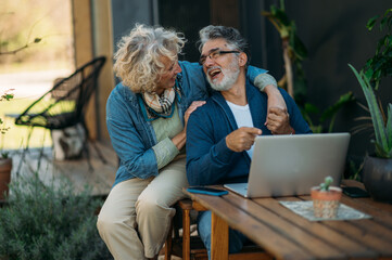 Middle age couple smiling confident using laptop in the garden.