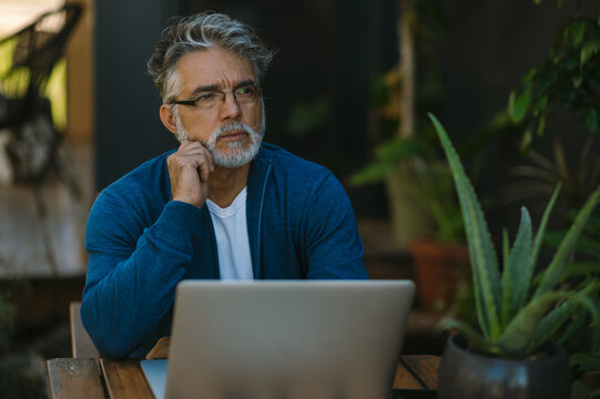 Handsome middle-aged man work on laptop in the garden.