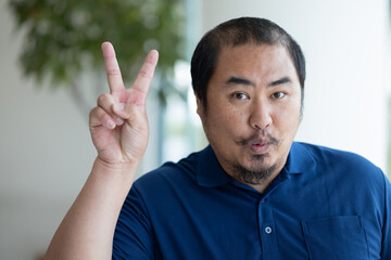 Confident happy smiling excited middle aged old asian man with hair loss pointing up 2 fingers, V...
