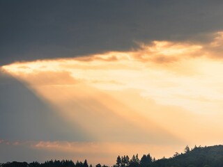 Naklejka premium Beautiful scene of Sunlight breaking through clouds over a peaceful countryside landscape