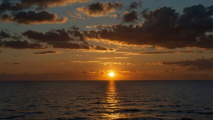Obraz premium Sun shine , A sunset over the ocean. Clouds are orange, yellow, and dark gray. The sun is low on the horizon.