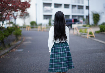 秋の昼の住宅街で歩くひとりの小学生の女の子の姿