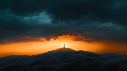 Silhouette of a person standing atop a mountain during a dramatic sunset.