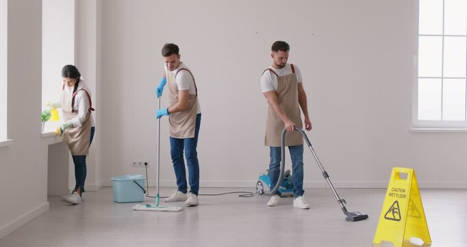 Cleaner group working, professional janitor service washing, vacuuming floor at home, office. Young people employed to take care of room, small company mopping, building maintenance and cleaning