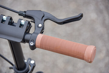 Brake lever on the scooter handlebar with beige handle.