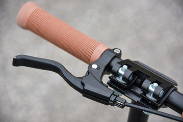 Brake lever on the scooter handlebar with beige handle.