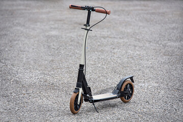 The folding scooter stands on the asphalt.