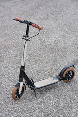 The folding scooter stands on the asphalt.