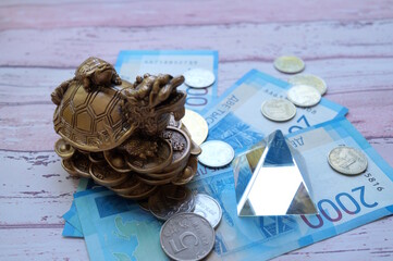 A dragon turtle statuette and a glass pyramid with paper bills.