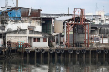 A small fish unloading bay with a large metal frame and pulley system is used for lifting or transferring fish containers, equipment, or supplies between boats and the dock, Phuket, Thailand.