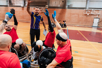 Happy coach with disabled rugby players cheering on wheelchair at sports court