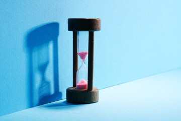 Hourglass with running sand over blue background
