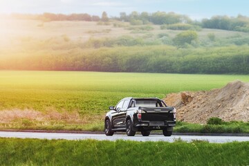 Fototapeta premium Black pickup truck driving through a scenic rural area