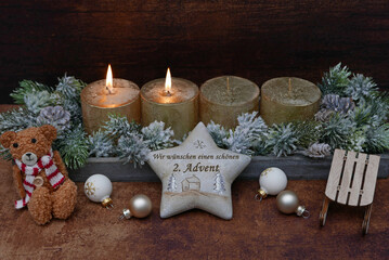 Dekoration zum zweiten Advent: Adventskranz mit goldenen Kerzen. Auf einem Stern steht der Text wir...