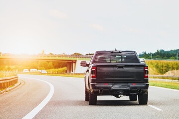 Black pickup truck on a road surrounded by nature