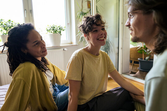 Happy multiracial friends spending leisure time talking with each other at home