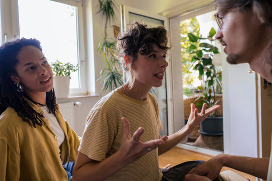 Young woman gesturing and talking with friend at home
