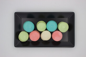 Assorted colorful macarons on black plate