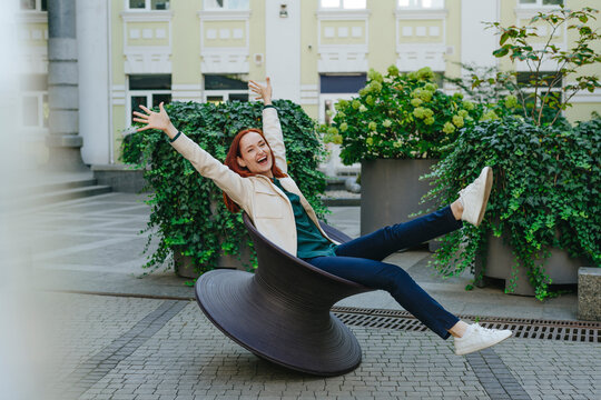 Happy businesswoman enjoying on spun chair in urban garden