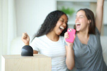 Happy friends singing at home with a smart speaker playing music