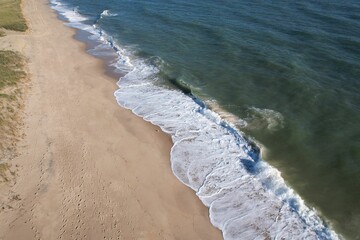 Aerial view of a sandy beach with gentle waves.