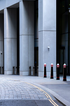 A clean and minimalist image of a building entrance adorned by simplistic bollards, emphasizing modern architectural design and urban safety functionality  in London UK