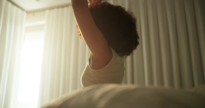 Woman, wake up and stretching on bed in home with morning routine or feeling fresh of sleeping. Back, person or arm movement in bedroom for start day, energy or wellness of break, resting and sunrise