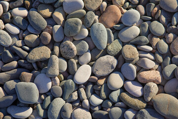 A close-up of a collection of smooth, multicolored pebbles and stones. These natural beach rocks display a variety of earthy tones and textures, creating a calming and organic aesthetic.