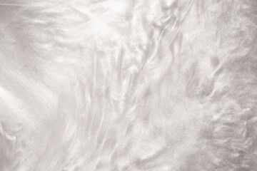 Shimmering silver abstract background. Liquid glitter paint texture waves and swirls. Beautiful shiny white glitter texture. Metallic silver paint close-up as a holiday background.