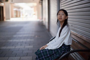 秋の昼の商店街で休憩する小学生の子供の様子