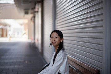 Fototapeta premium 秋の昼の商店街で休憩する小学生の子供の様子