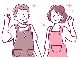 笑顔でガッツポーズするエプロン姿の中年の夫婦