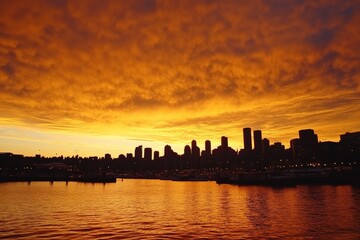 Fototapeta premium An awe-inspiring silhouette of a city under a dramatic golden sky filled with layered clouds, capturing the timeless beauty and serenity of twilight in an urban setting.