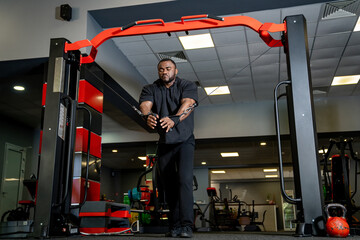 Man using cable machine at gym evening. A dedicated individual exercises with a cable machine in the gym during the evening, focusing on strength training.