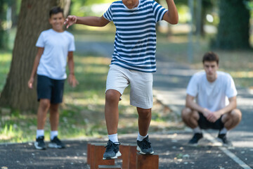 Obraz premium Two boys participate in outdoor sports activities, balancing across wooden stumps under the guidance of a trainer. The natural setting fosters coordination and focus during this playful exercise.