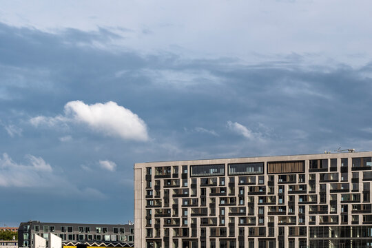 A sleek modern housing complex stands boldly against a vivid sky, emphasizing the blend of contemporary architectural design and dramatic natural backdrops in Rotterdam